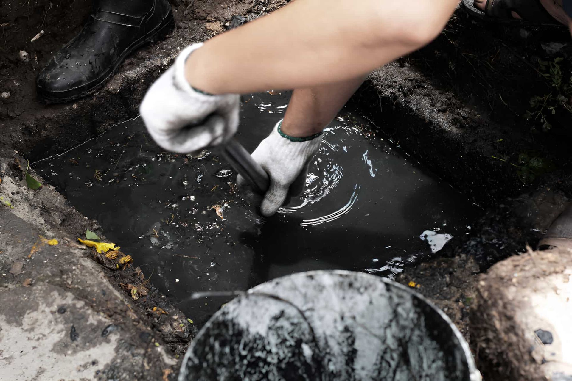 A Person Is Cleaning A Drain With A Shovel And A Bucket — Gillen Plumbing In Ciccone, NT