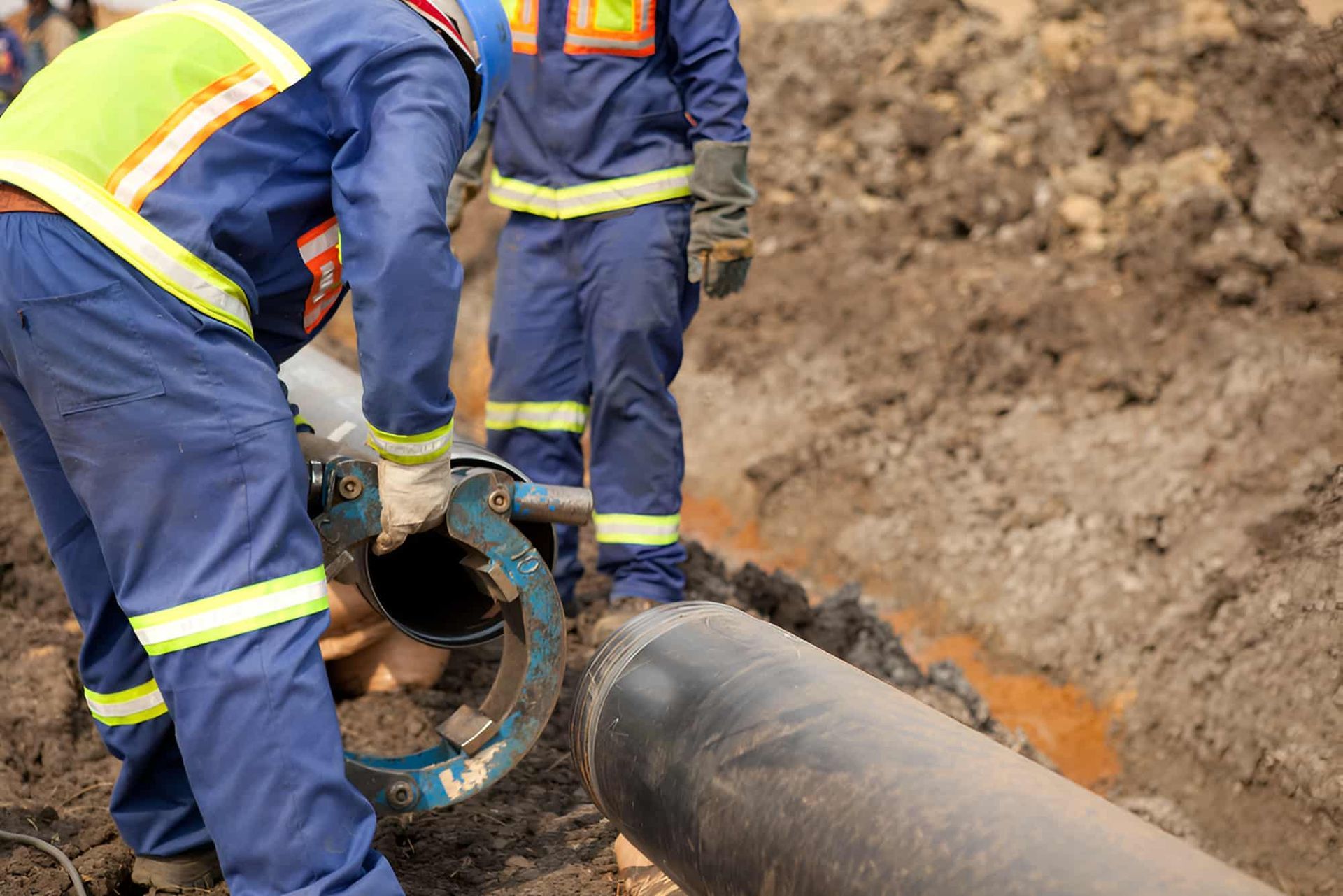A Group Of Construction Workers Are Working On A Pipe In The Dirt — Gillen Plumbing In Ciccone, NT