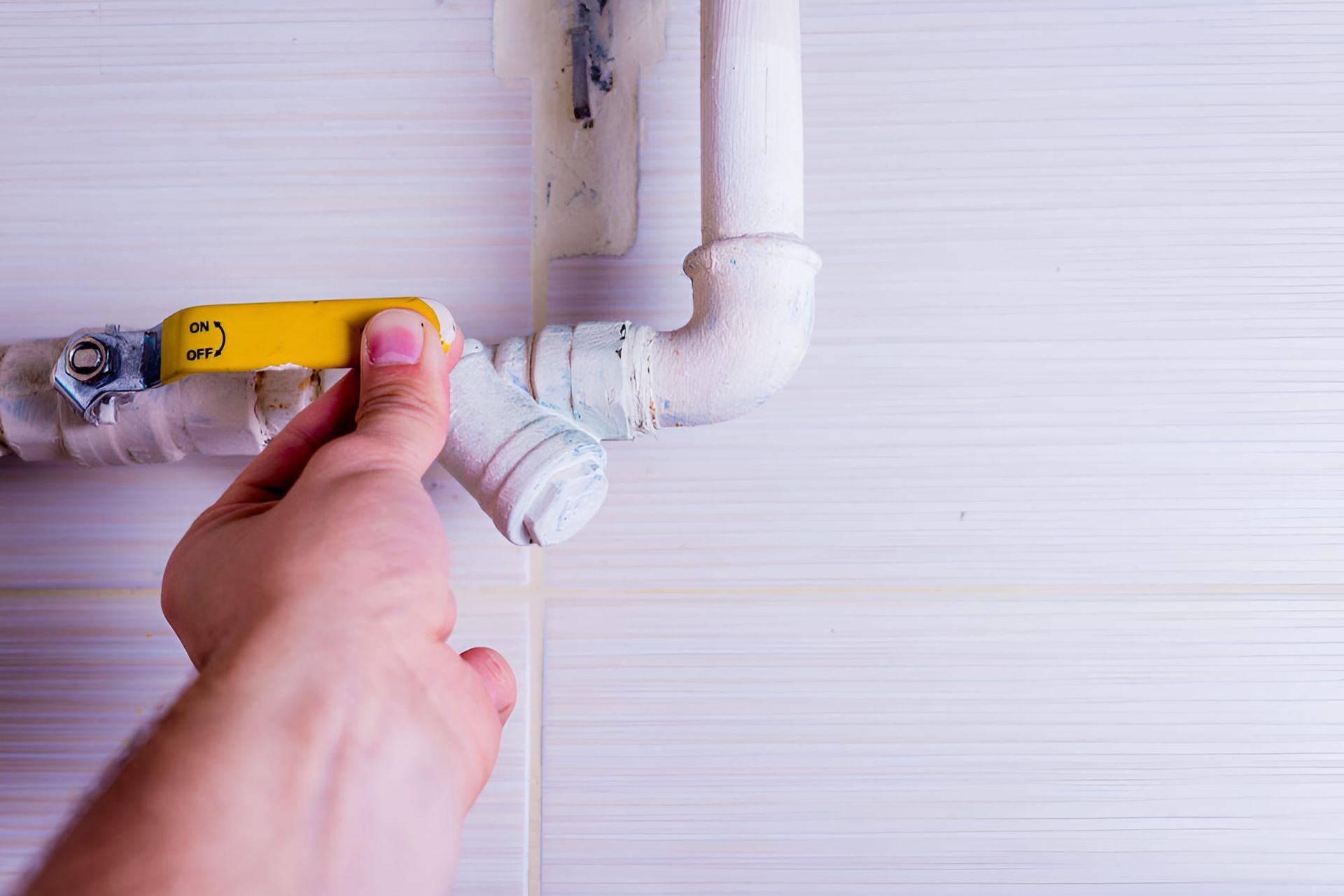 A Person Is Fixing A Pipe With A Yellow Valve — Gillen Plumbing In Ciccone, NT