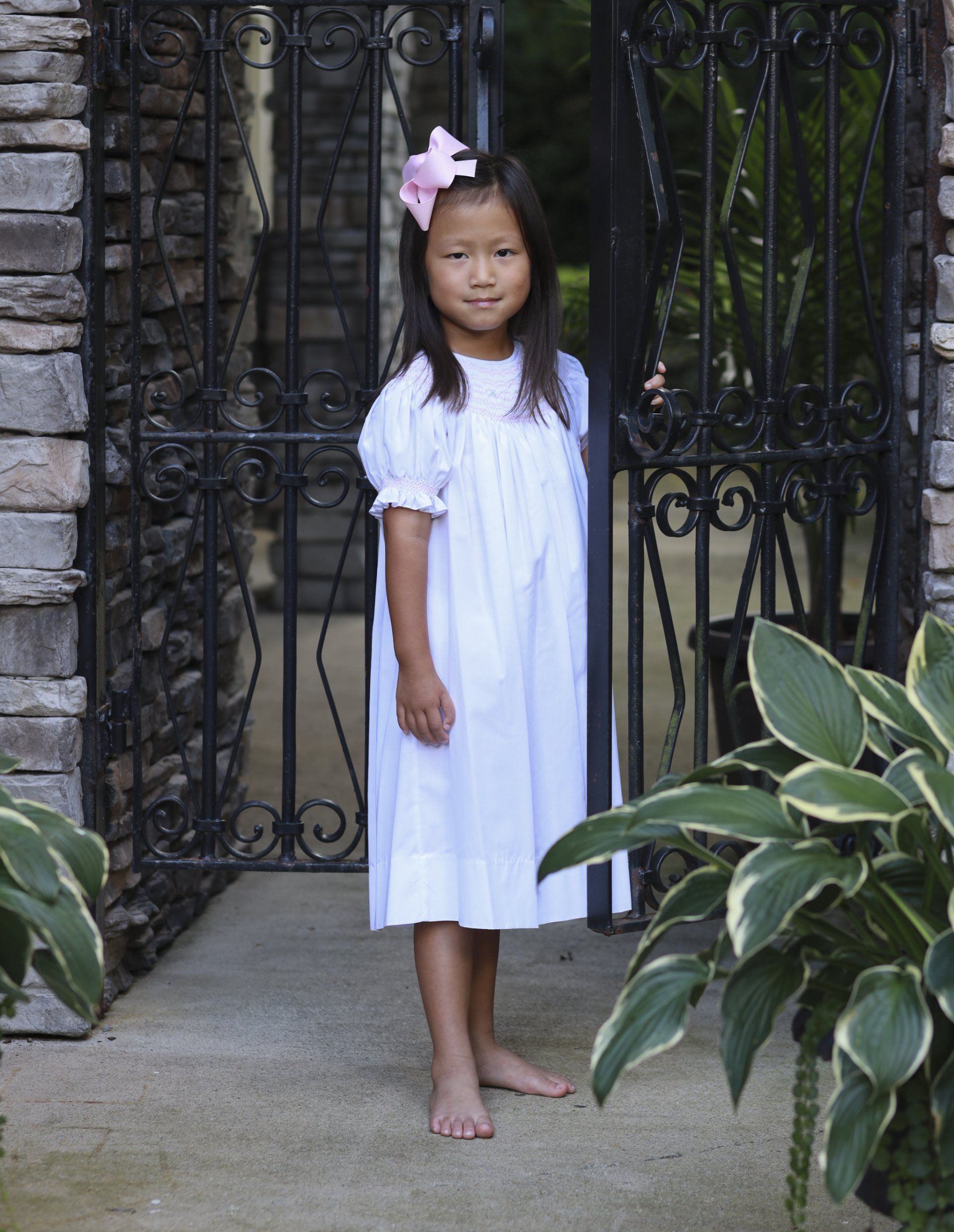 Outdoor photograph of girl standing by gate