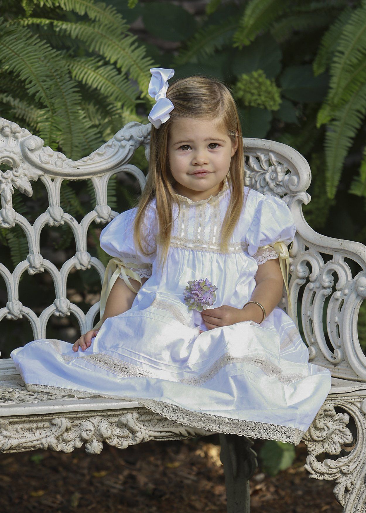 Outdoor photo of child sitting on white bench