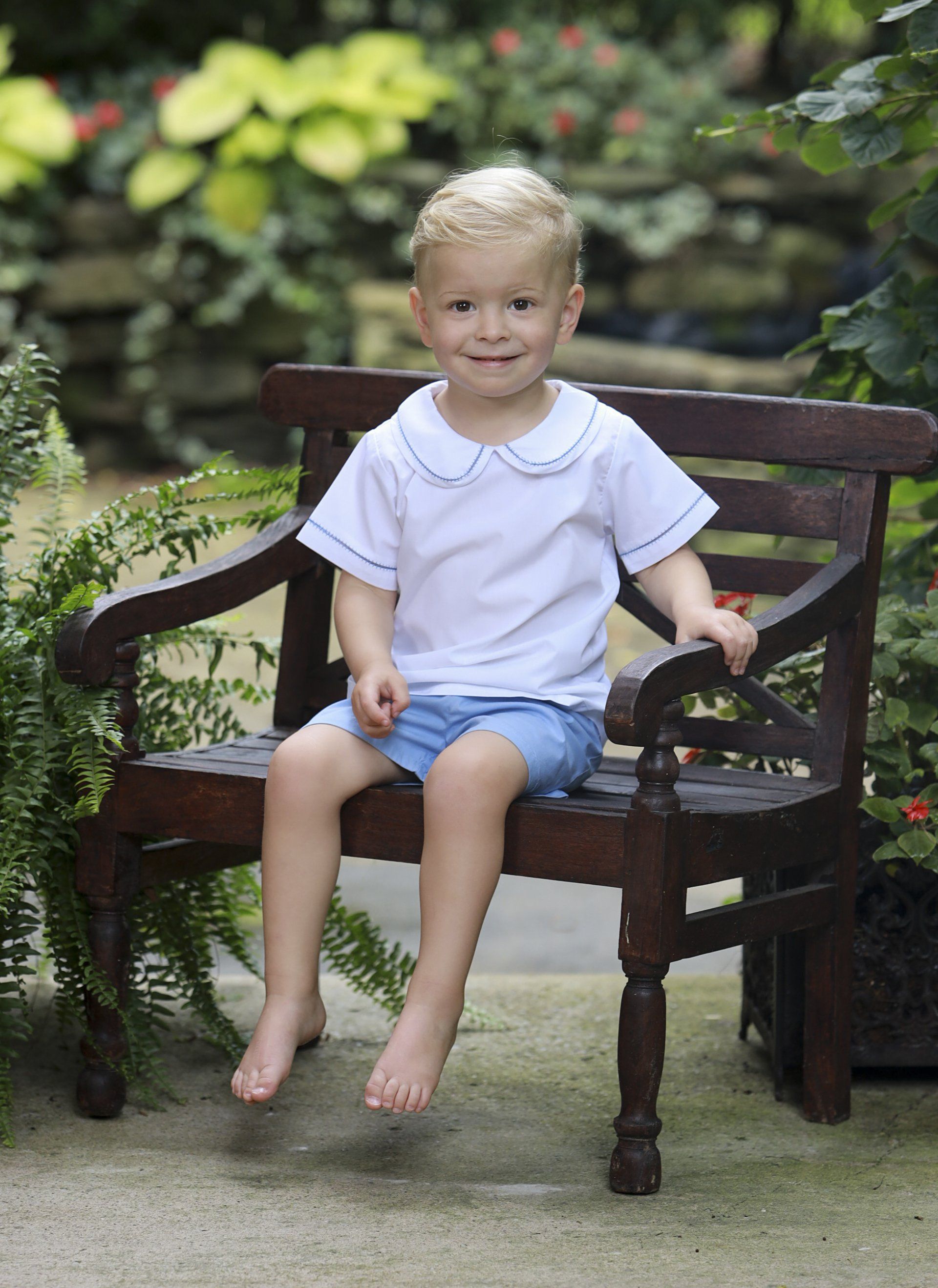 Outdoor photo of young boy sitting on bench