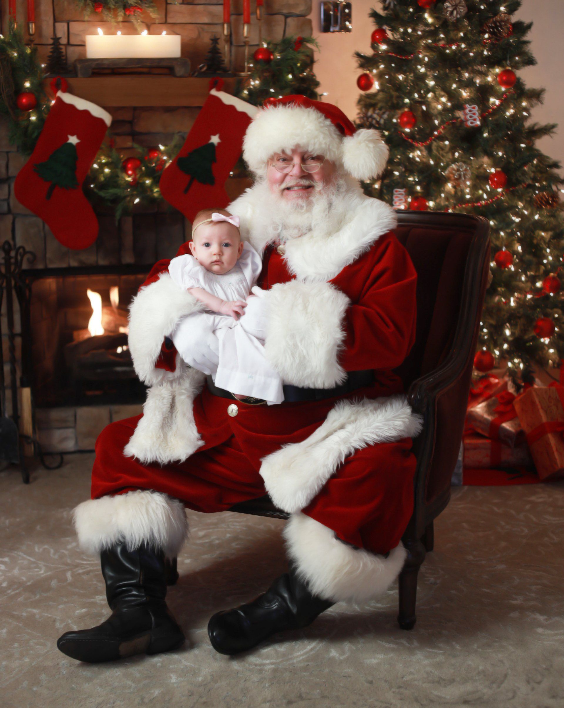 Santa holding baby in front of Christmas tree
