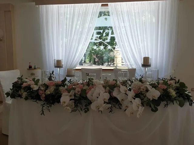 Un tavolo ricoperto da una tovaglia bianca, decorato con un lussureggiante centrotavola floreale di orchidee bianche