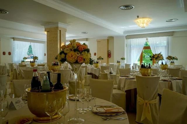 Una sala da pranzo allestita per un evento formale con tavoli rotondi