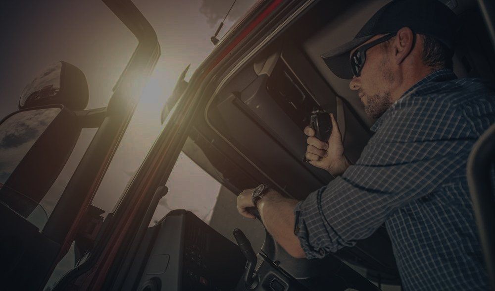 A man is driving a truck and talking on a radio