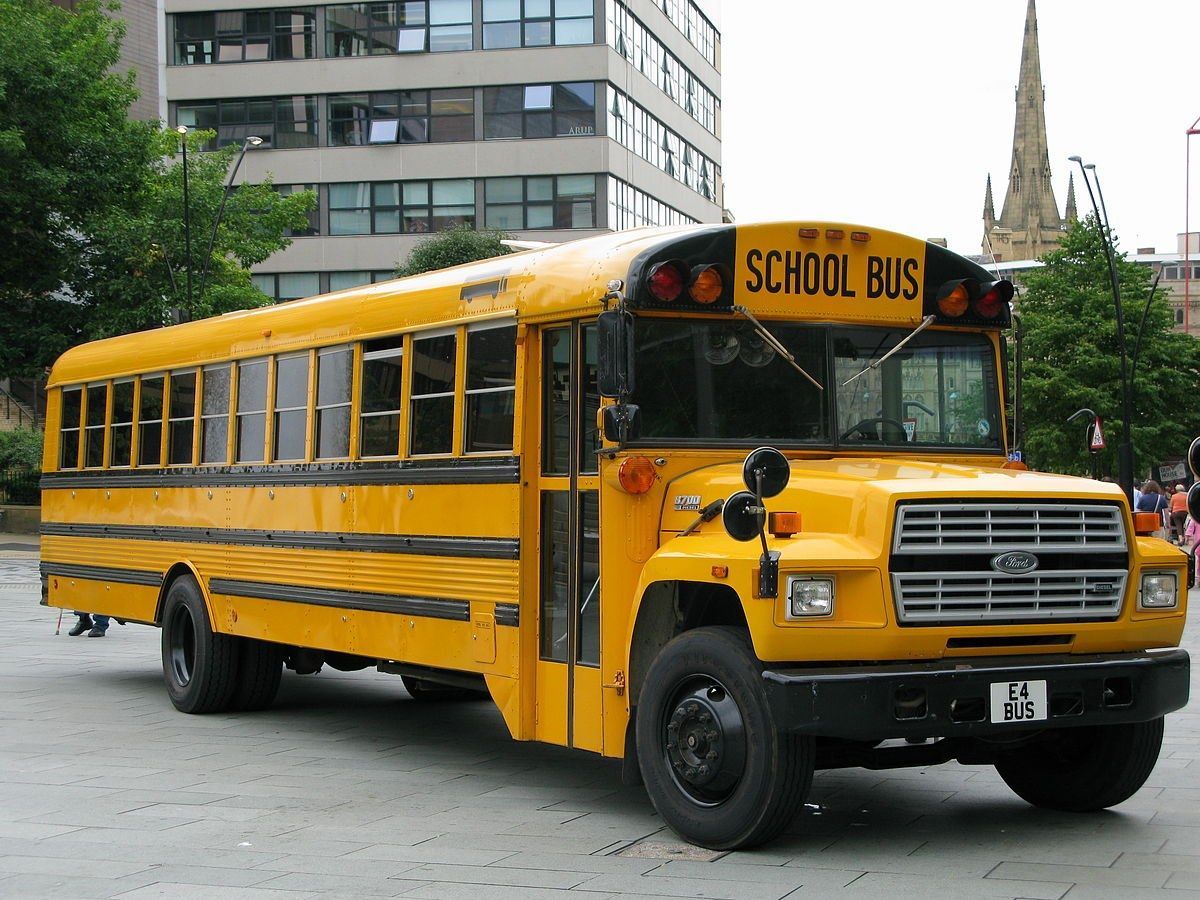 A yellow school bus is parked in front of a building