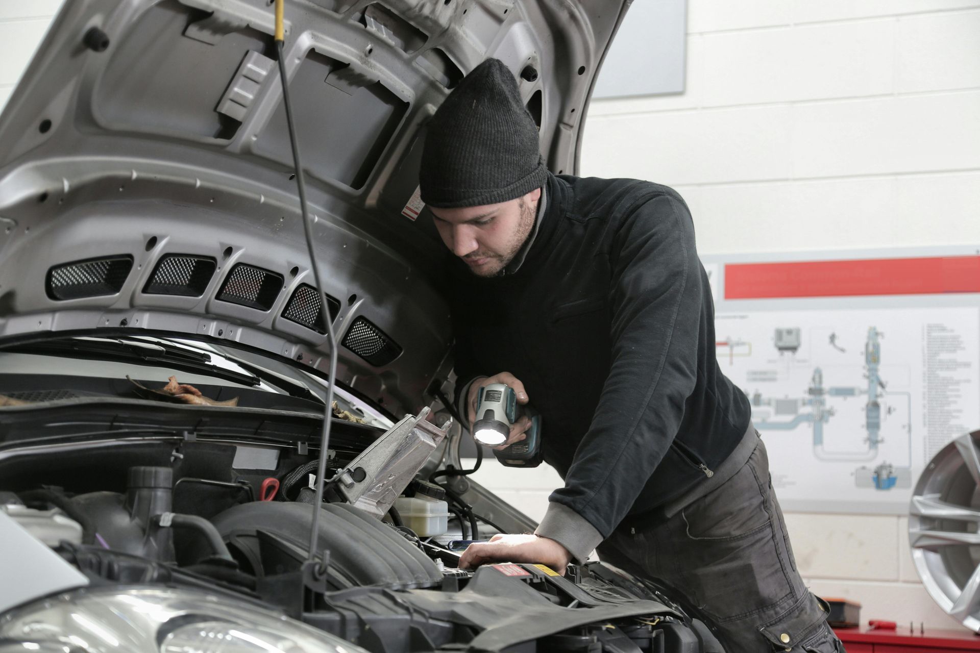 A man is working on the engine of a car with the hood open.