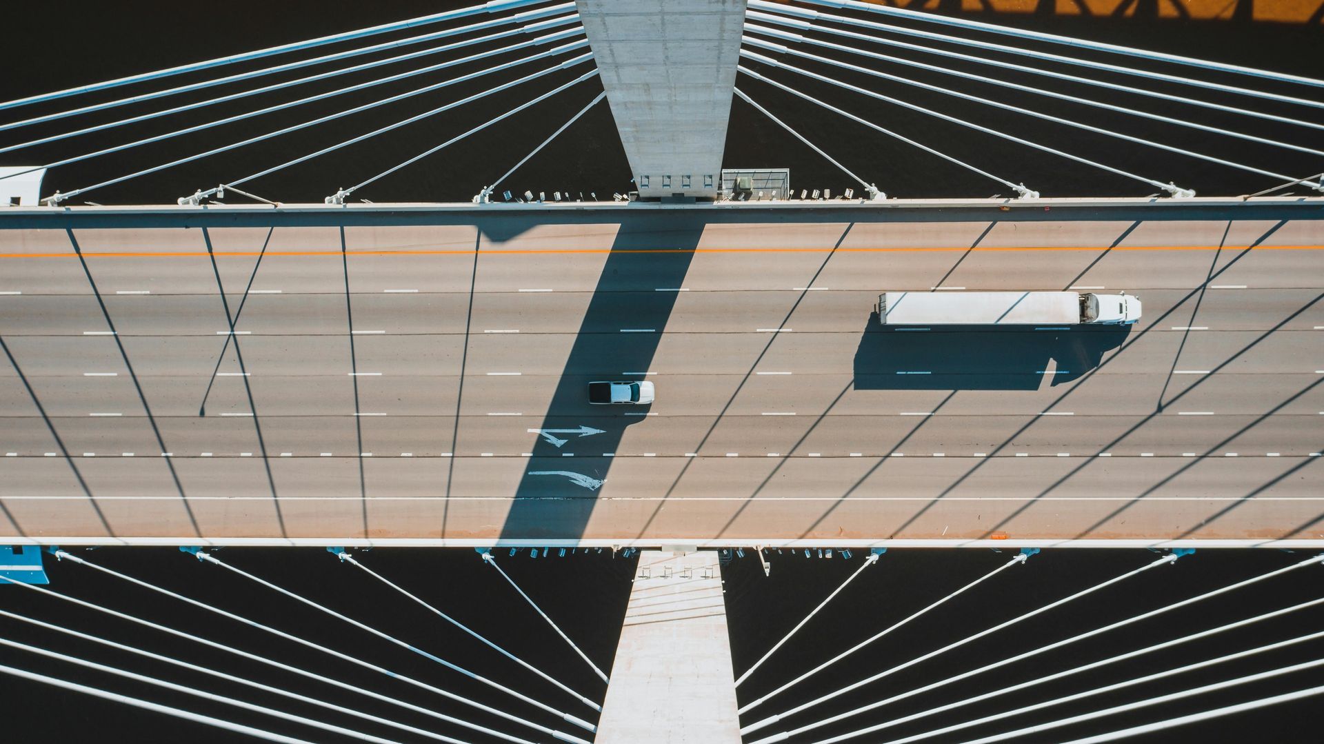 An aerial view of a bridge with cars and trucks driving on it.