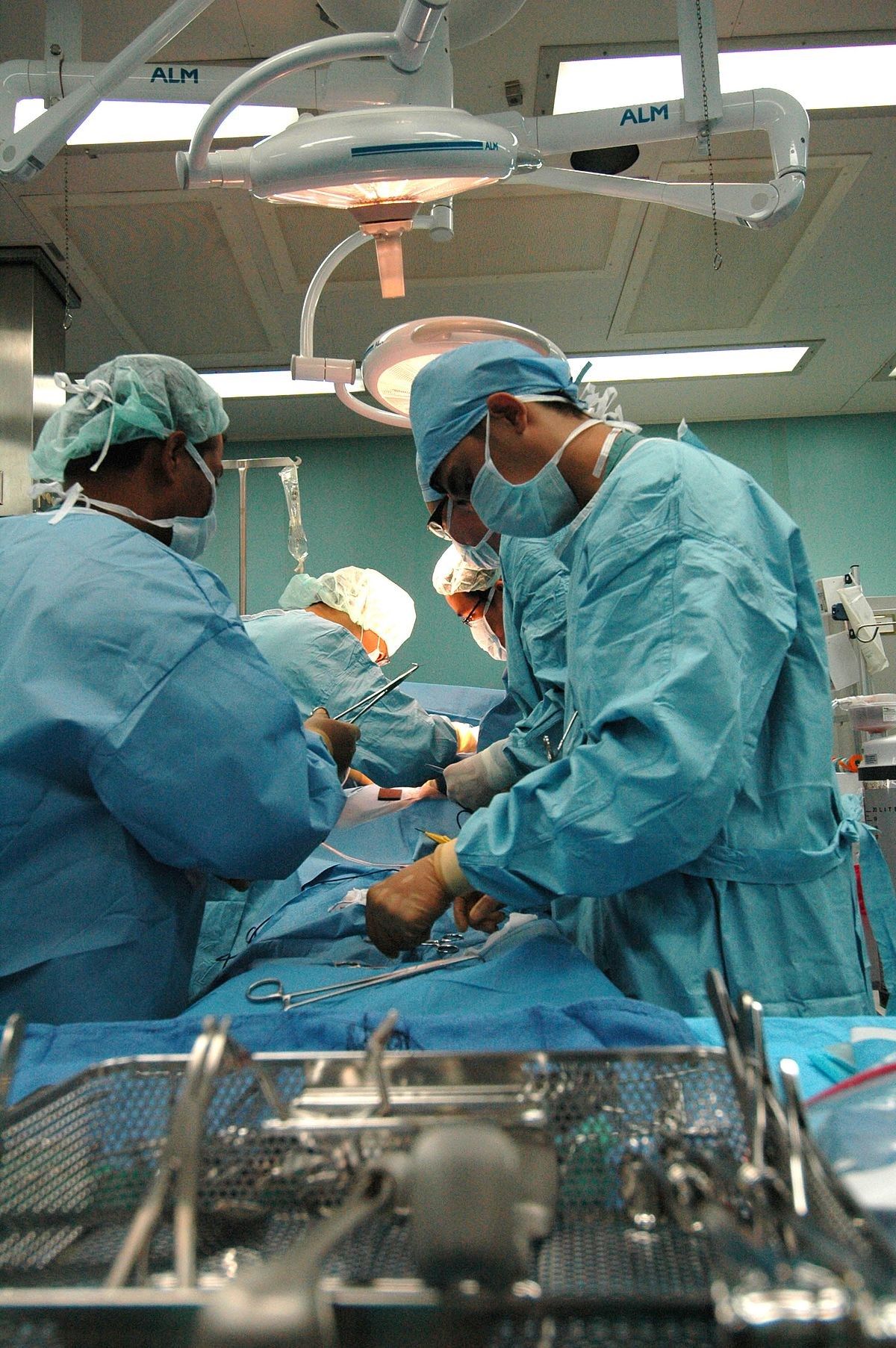A group of surgeons are performing surgery on a patient in an operating room.
