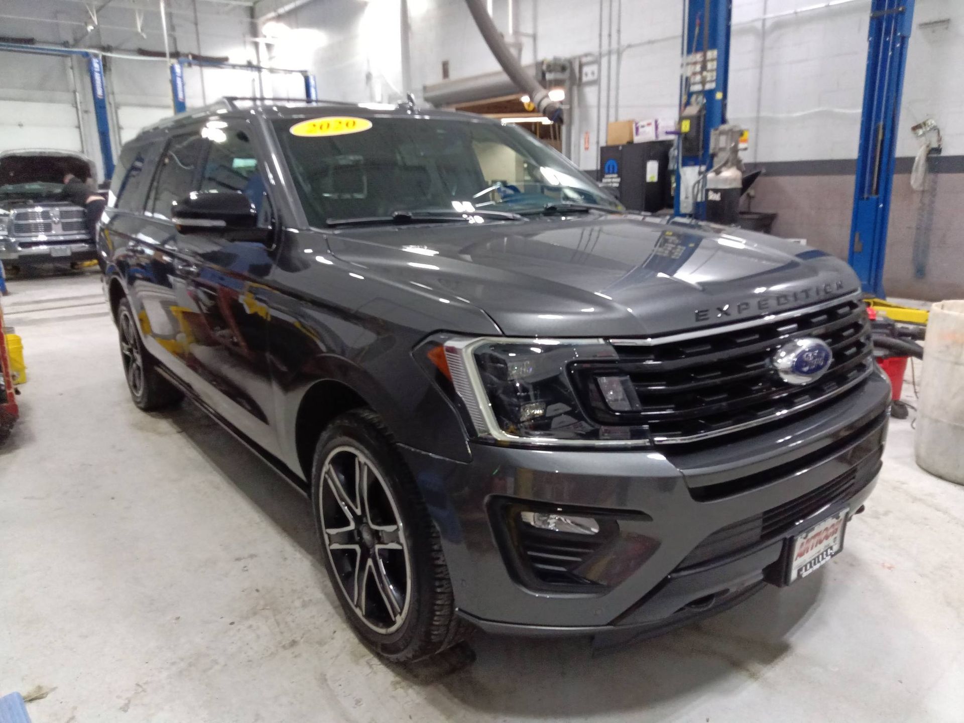 Black Ford SUV in an auto shop, parked indoors under bright lights.