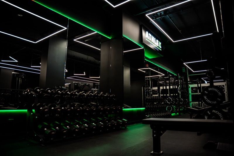 Une salle de sport avec beaucoup d'haltères et de lumières vertes.