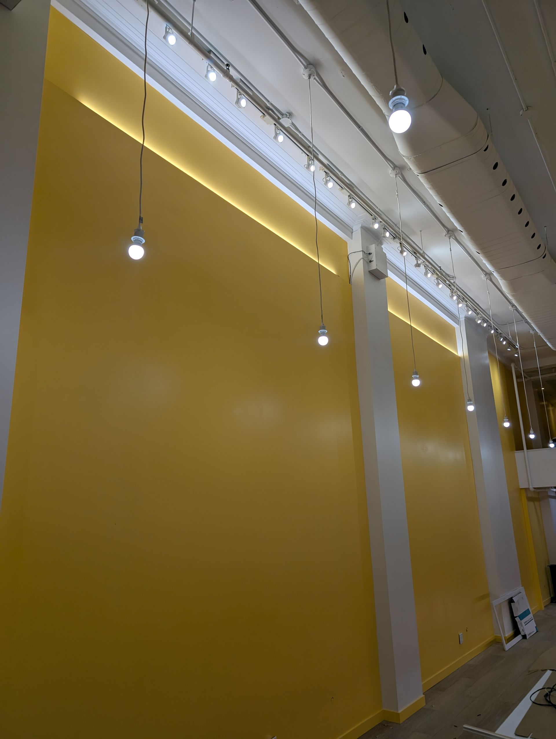 Un mur jaune avec beaucoup de lumières suspendues au plafond