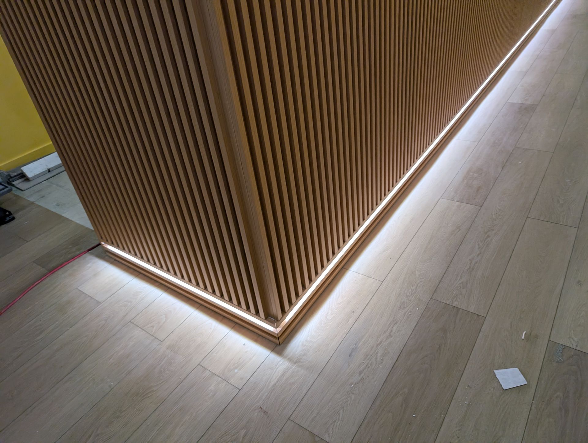 Un mur en bois avec une lumière derrière et un plancher en bois.