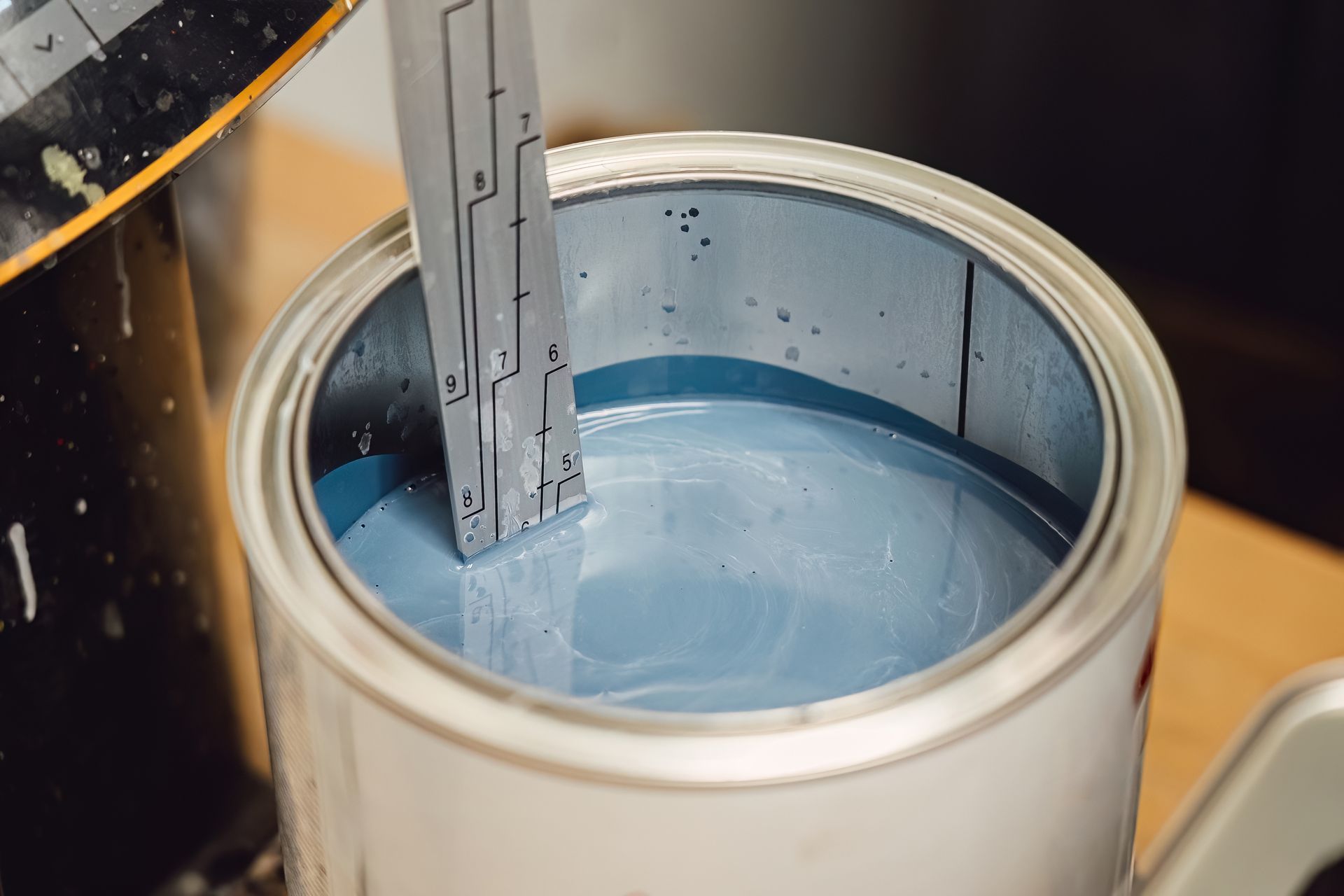 A paint can filled with light blue paint as a mixer blade stirs inside it.