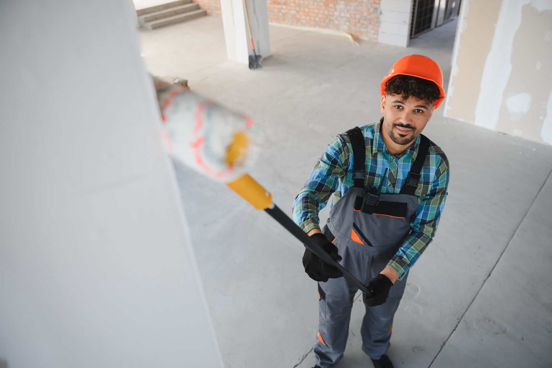 Painter rolling white paint on a wall in a bright indoor space