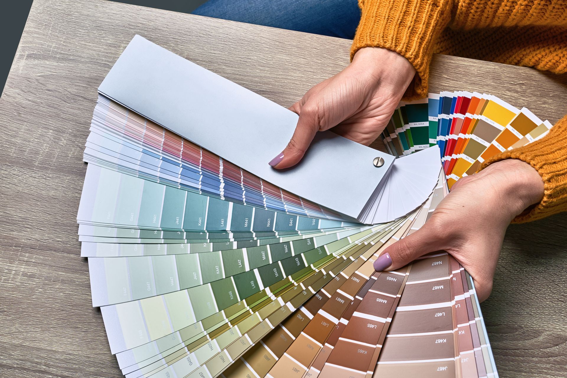 Hands flipping through a fan of paint color swatches on a couch