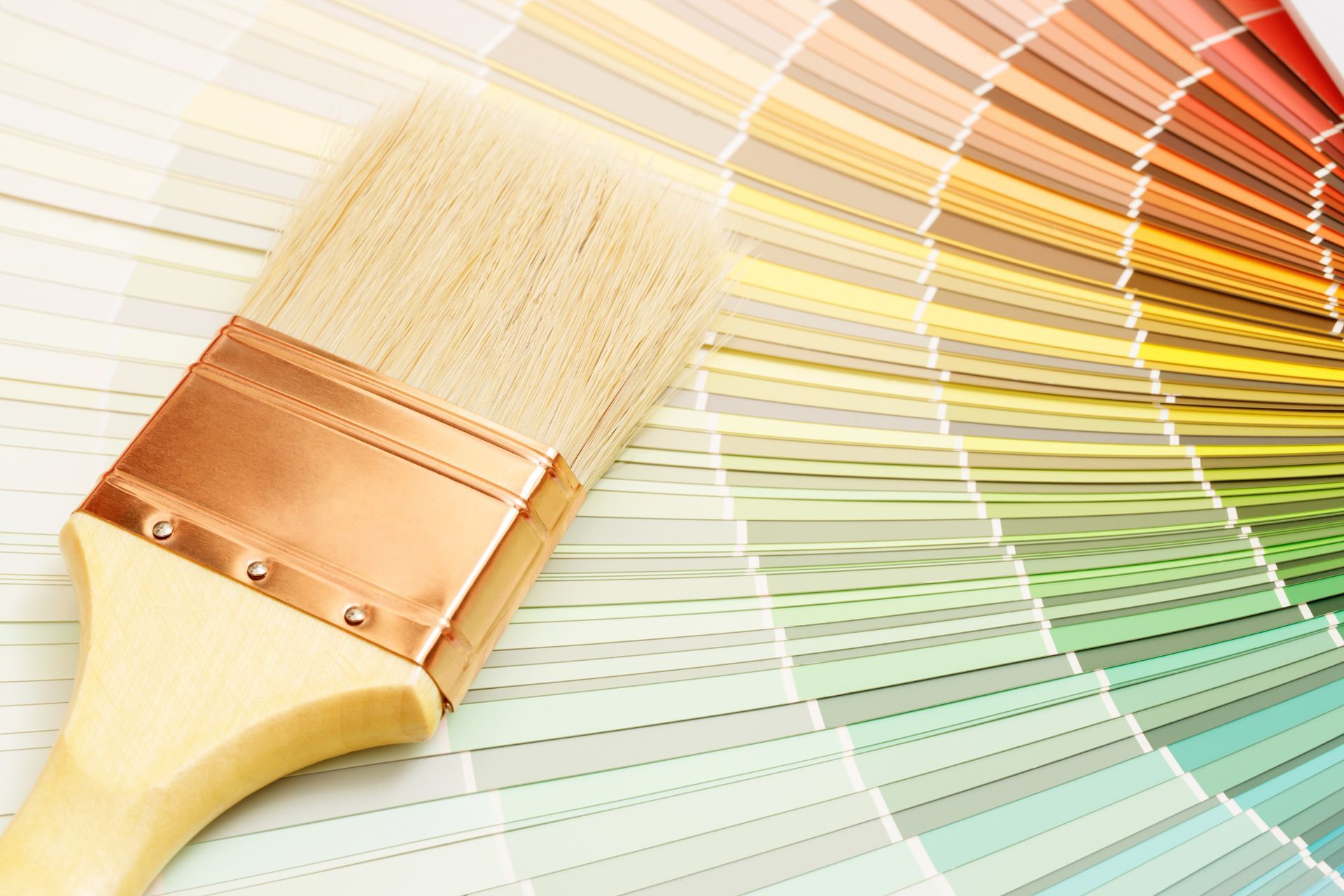 Paintbrush over a fan of pastel color swatches