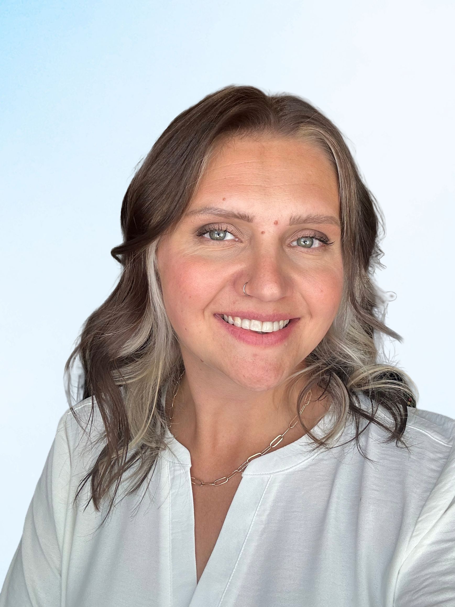 A woman in a white shirt is smiling for the camera.