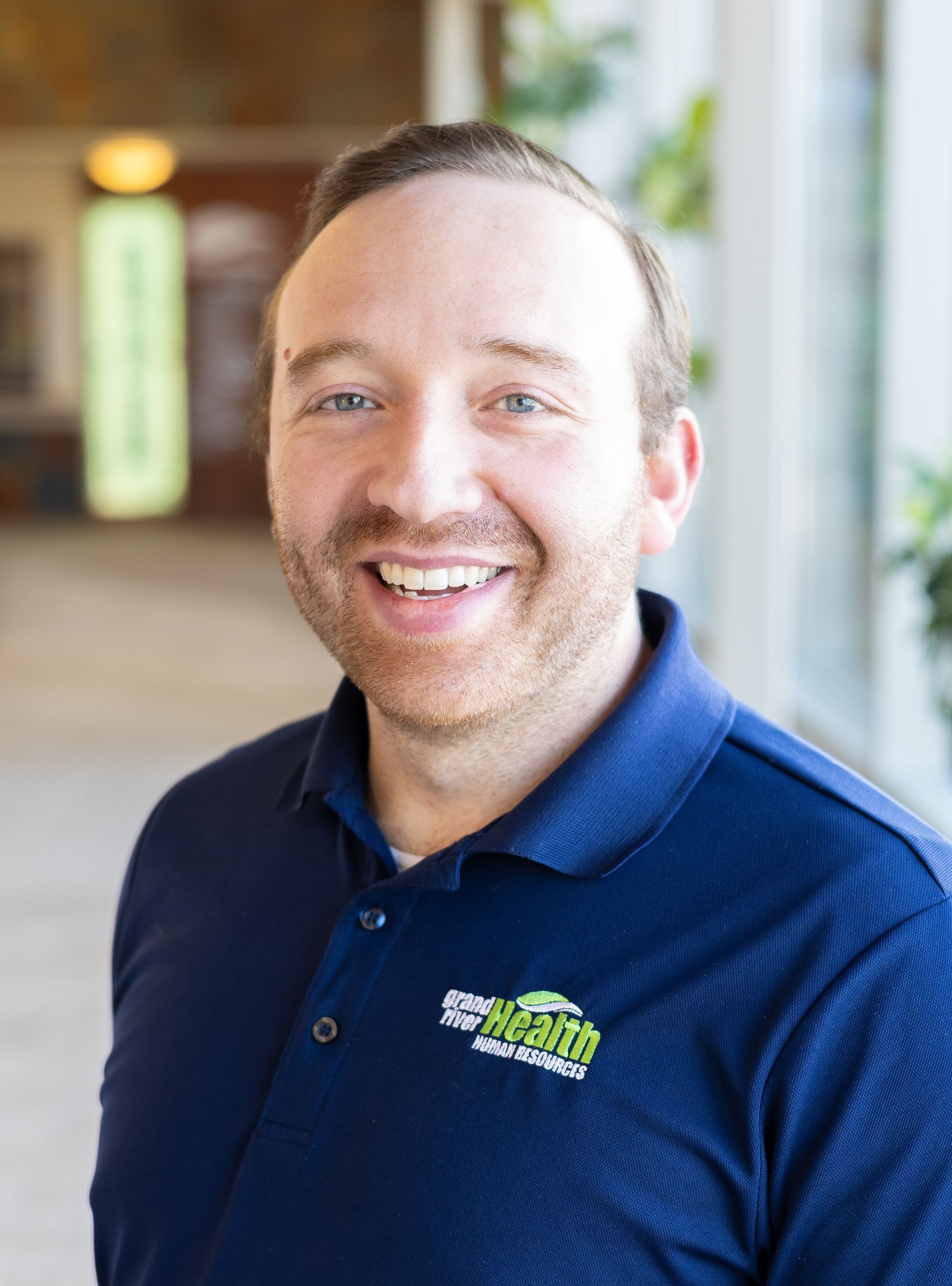 A woman in a sweater and vest is standing in front of a brick wall.