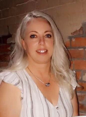 A woman is sitting in front of a brick wall.