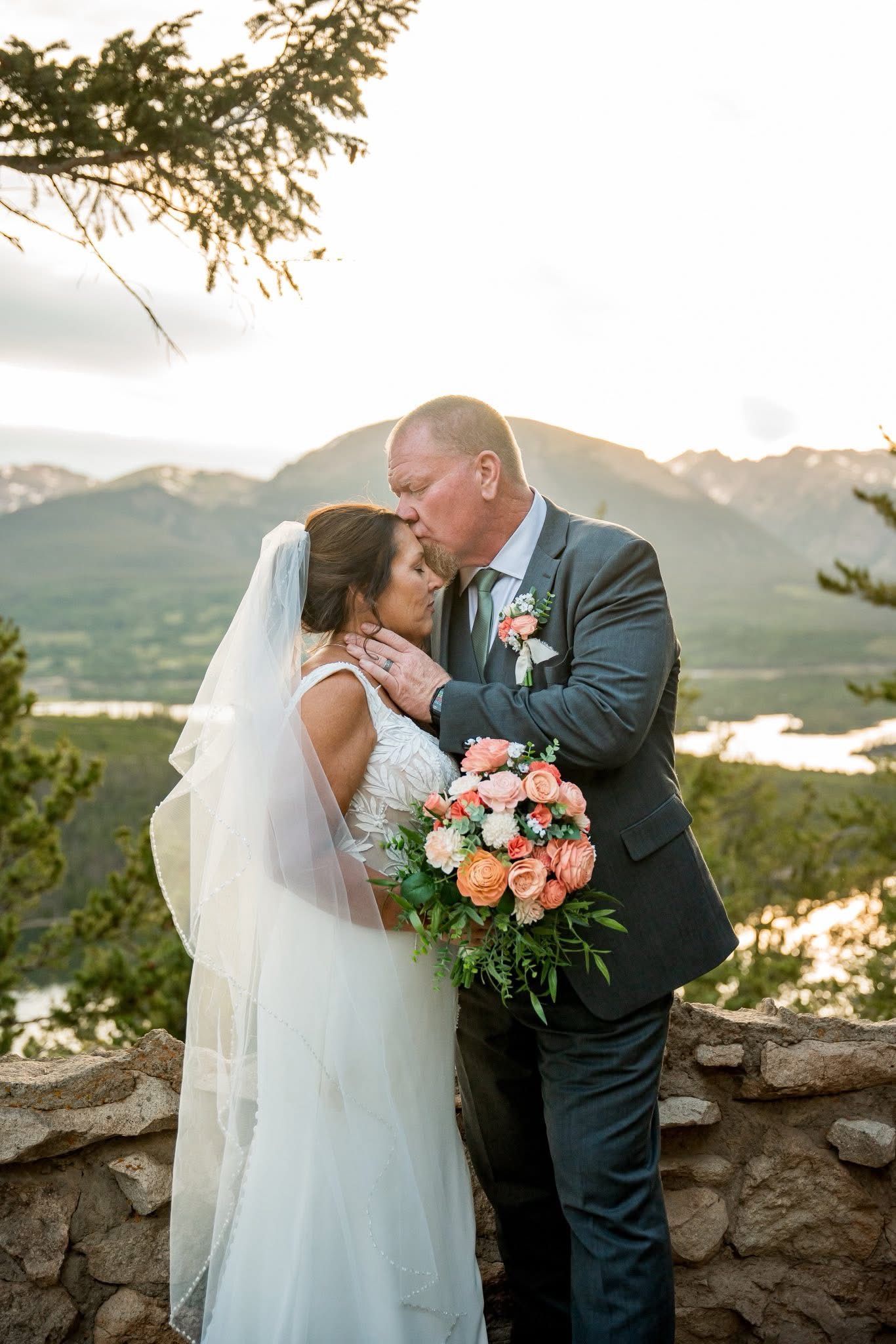 groom kissing bride of forehead