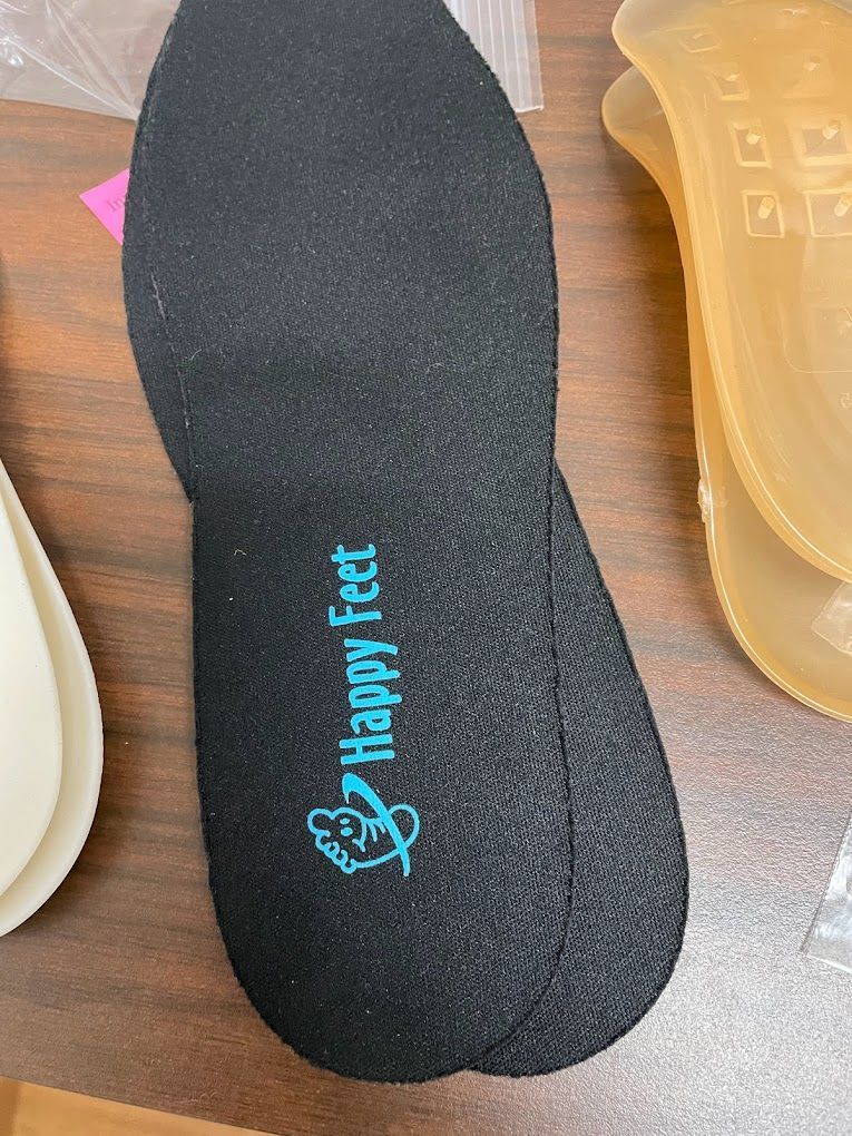 A pair of happy feet insoles are sitting on a wooden table.