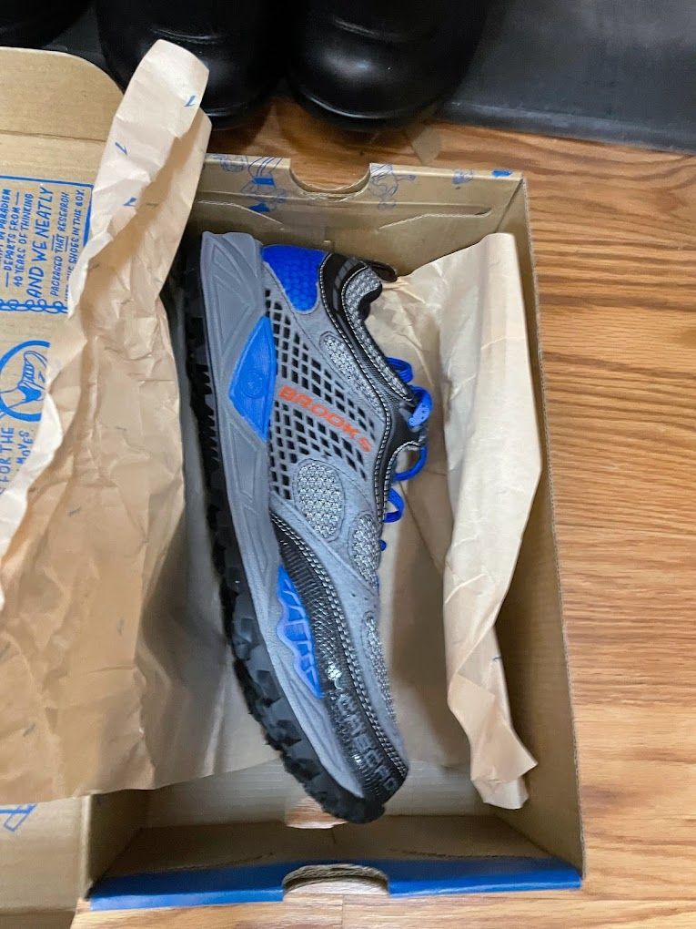 A pair of shoes are sitting in a box on a wooden floor.