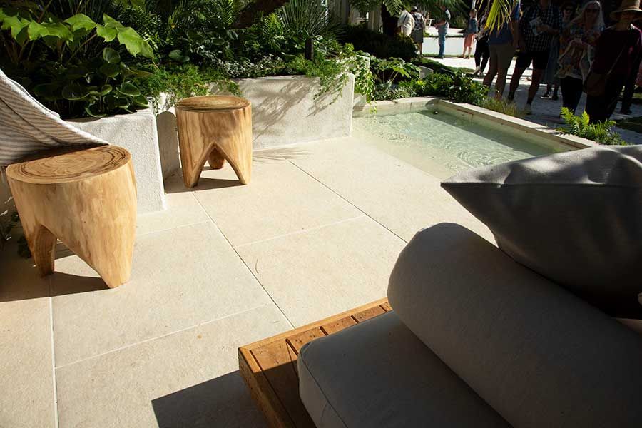 Outdoor patio with lounge furniture, small pool, and tree-stump stools.
