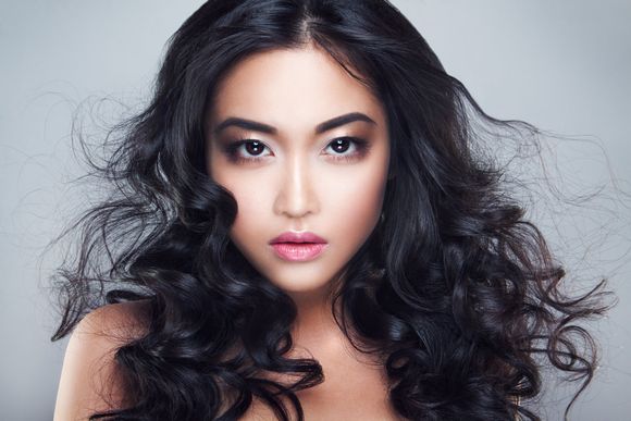 A woman with long curly hair is looking at the camera.