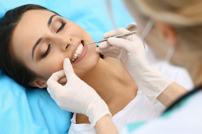 A woman is having her teeth examined by a dentist.