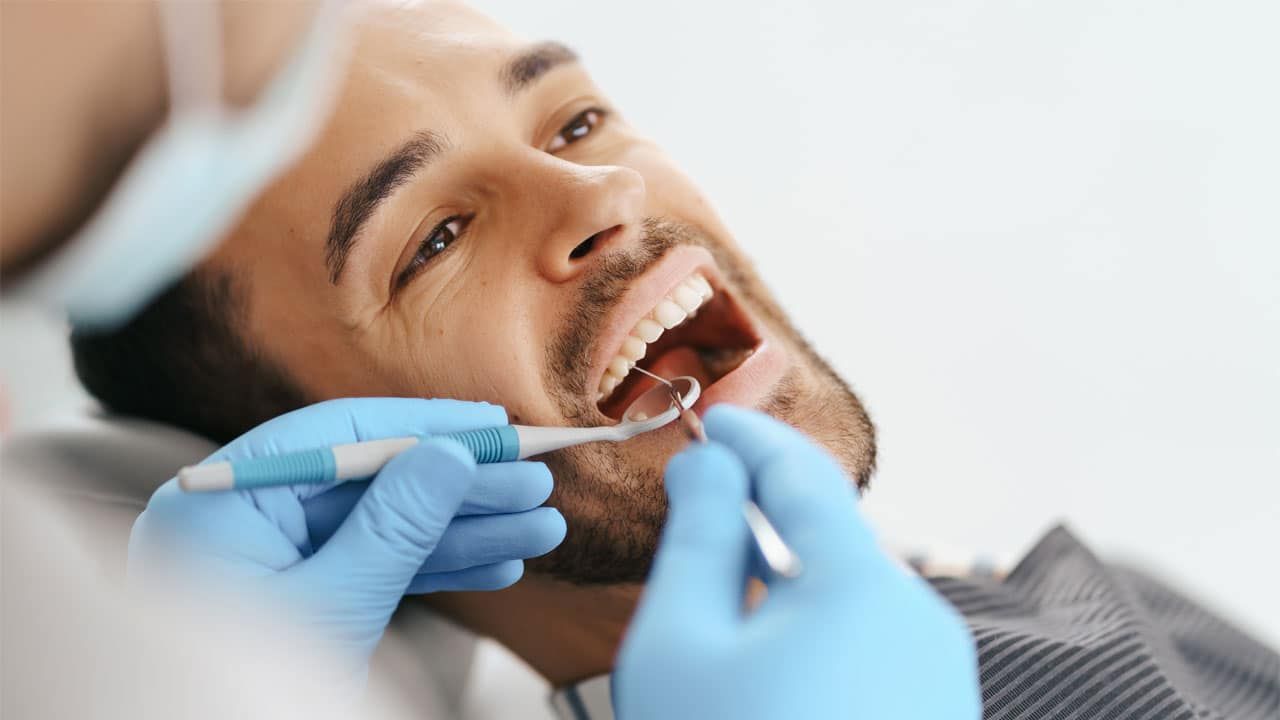 A man is getting his teeth examined by a dentist.