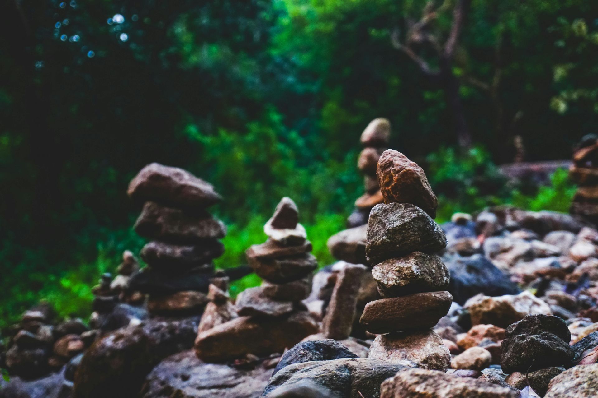 River rocks stacked vertically in front of a lush, green background