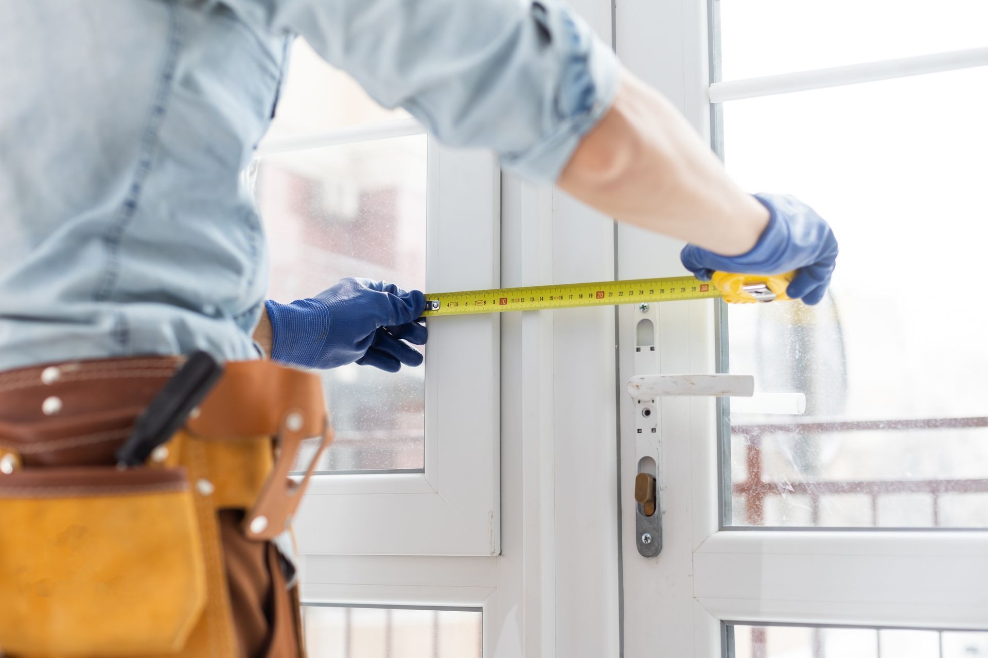 Installer measuring a white door with a tape measure in a bright room