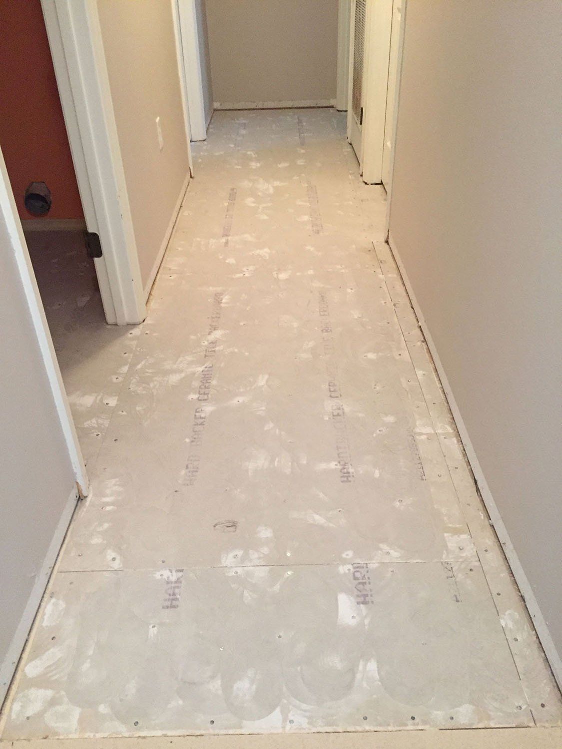 A hallway with a white tile floor in a house.
