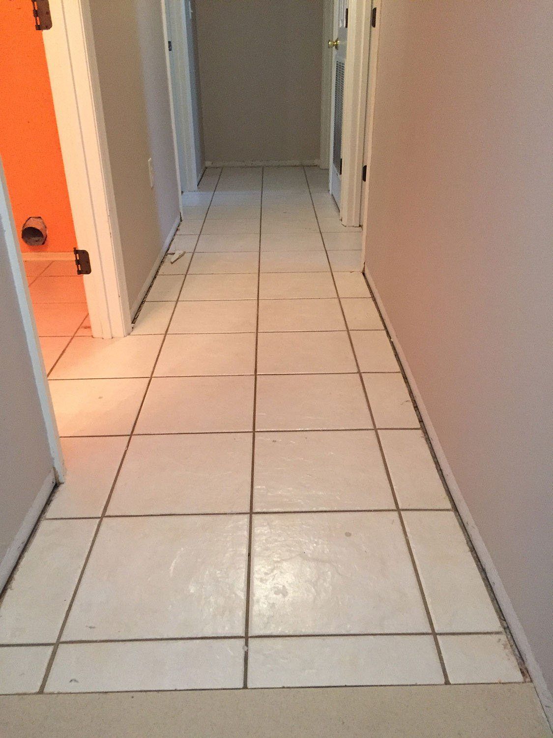 A hallway with white tile floors leading to a bathroom.