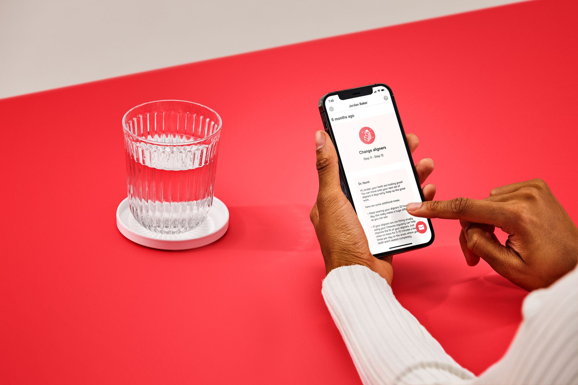 A person is using a cell phone next to a glass of water.