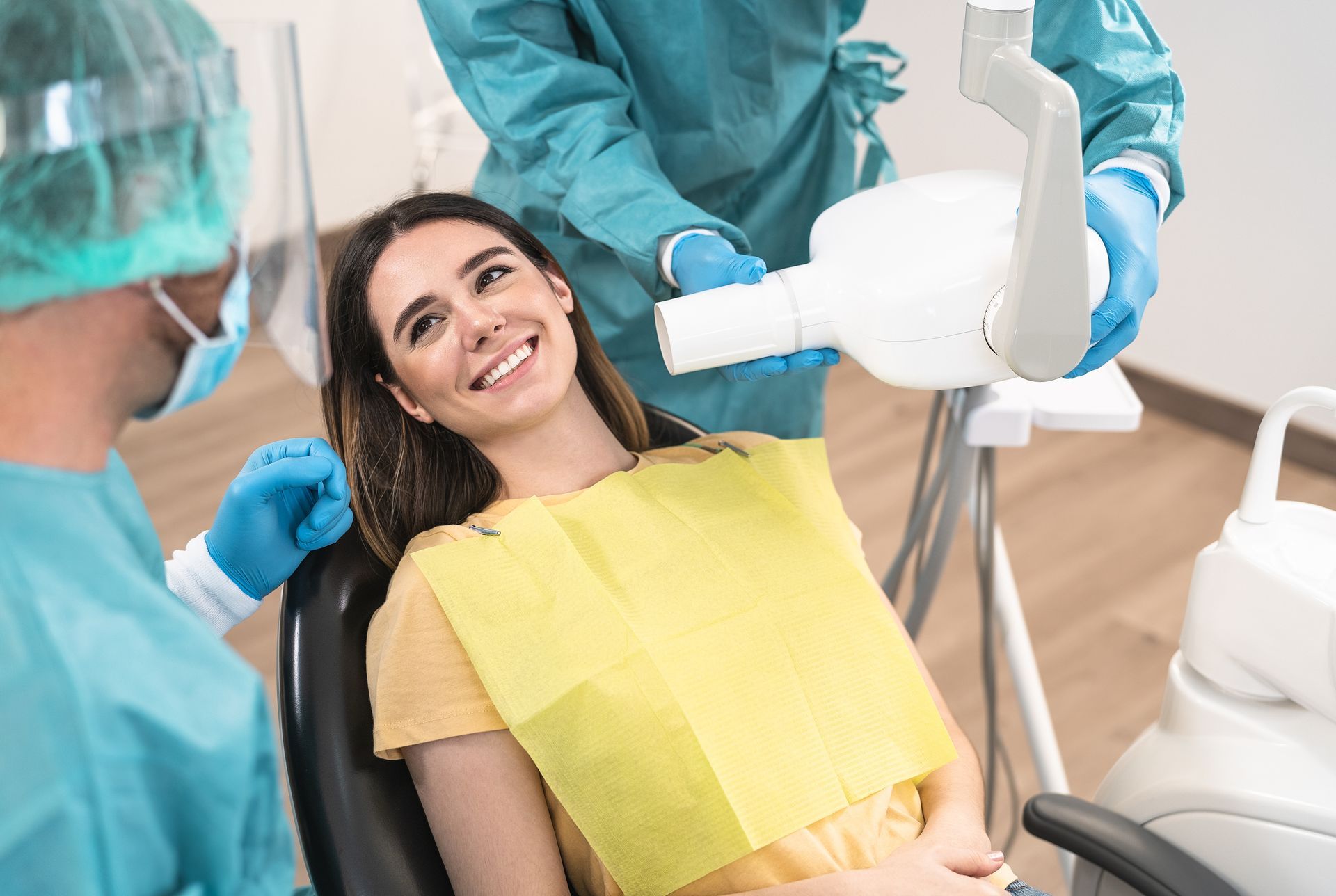 A woman is smiling while sitting in a dental chair.