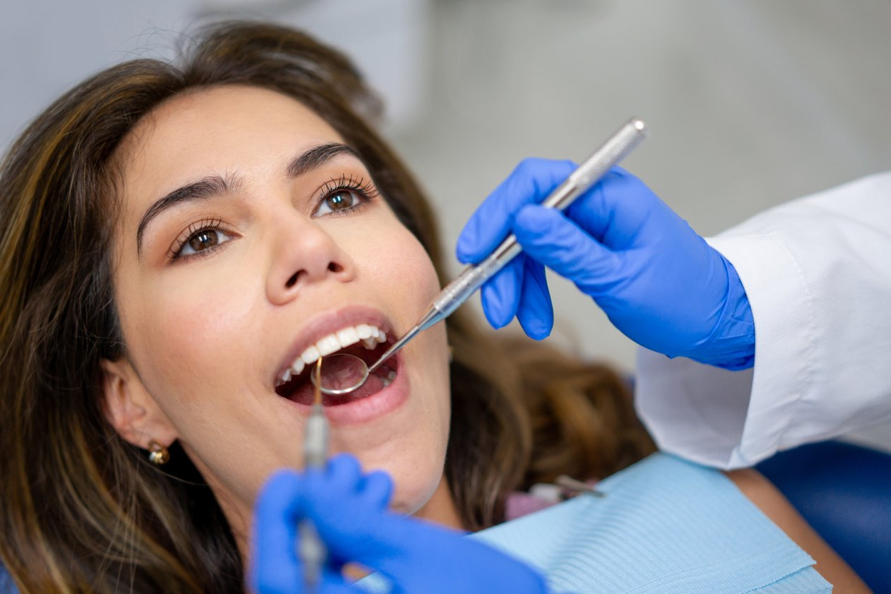 A woman is getting her teeth examined by a dentist.