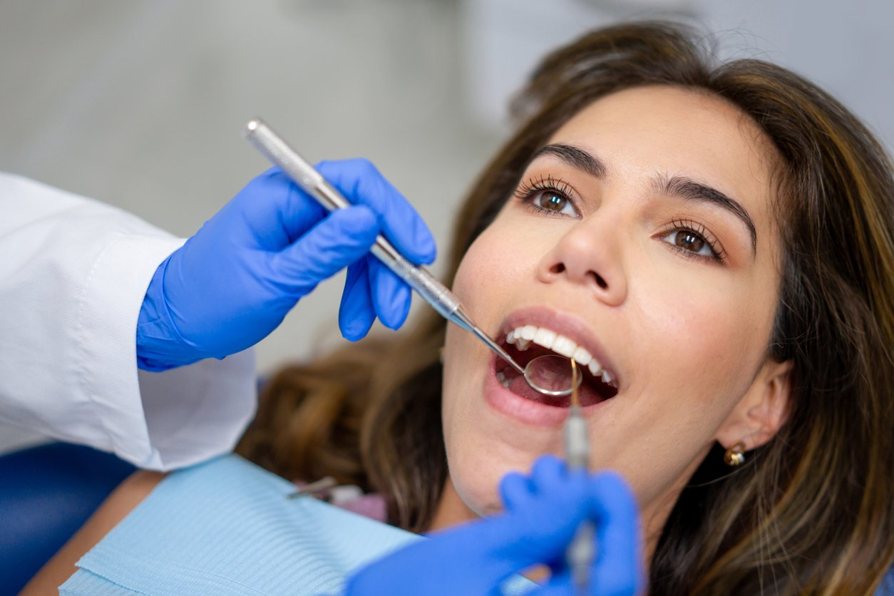 A woman is getting her teeth examined by a dentist.