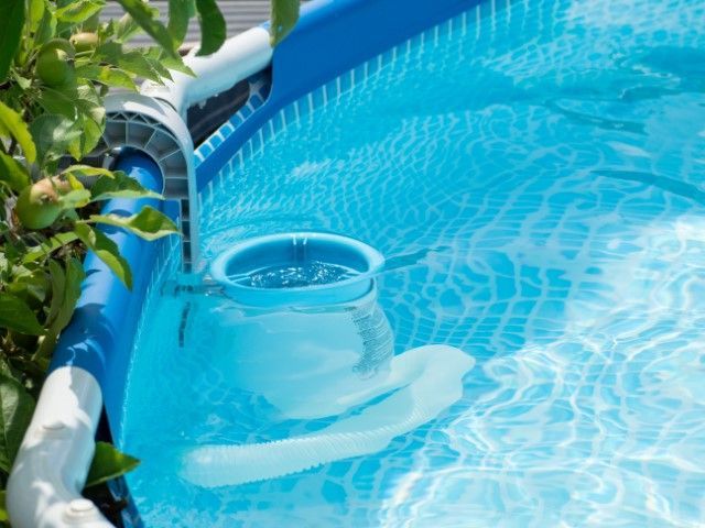 Above-ground pool with clear blue water and skimmer, blue and white structure.