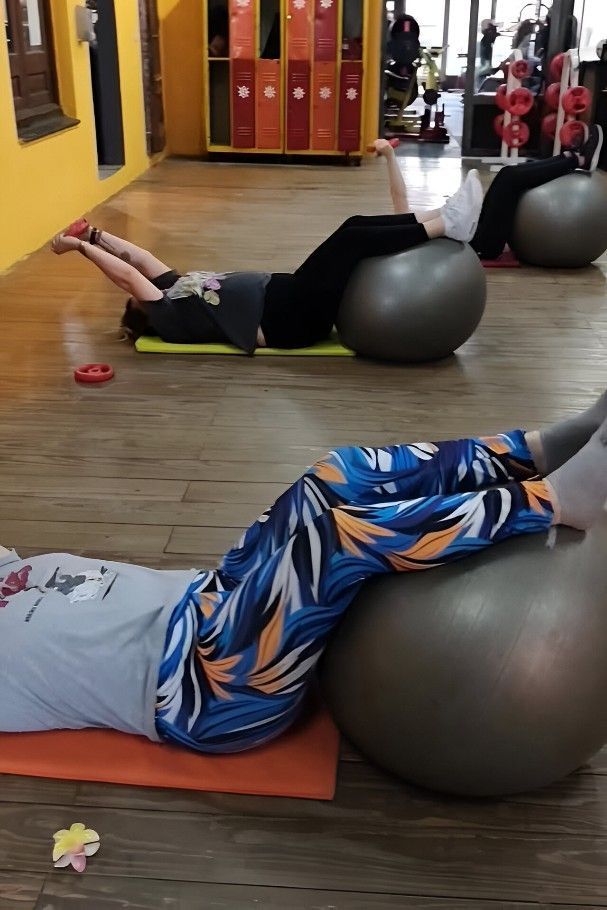 Personas haciendo ejercicio con balones de fitness en un gimnasio.