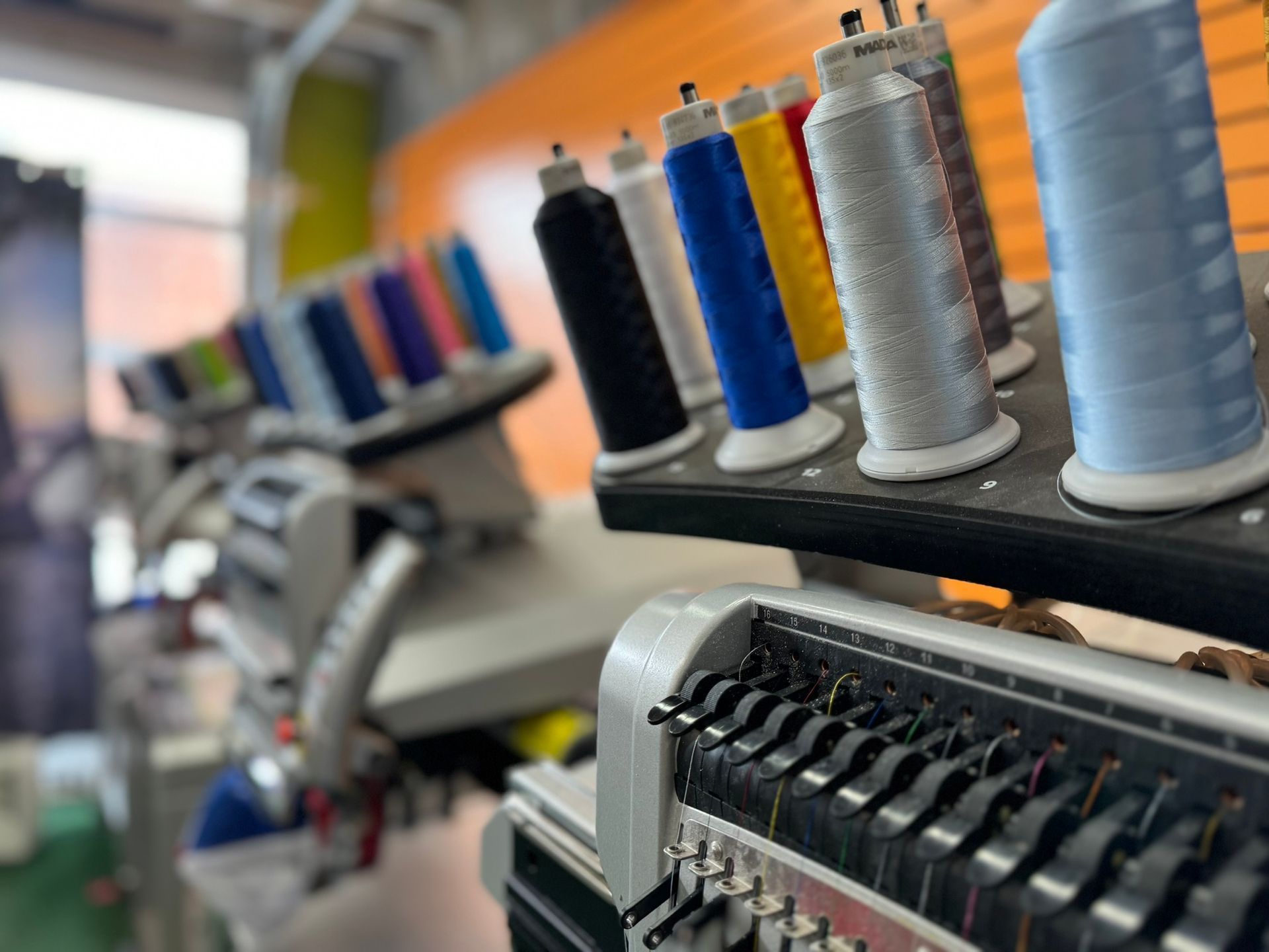 Embroidery machine with colorful thread spools in a workshop, ready to create designs.
