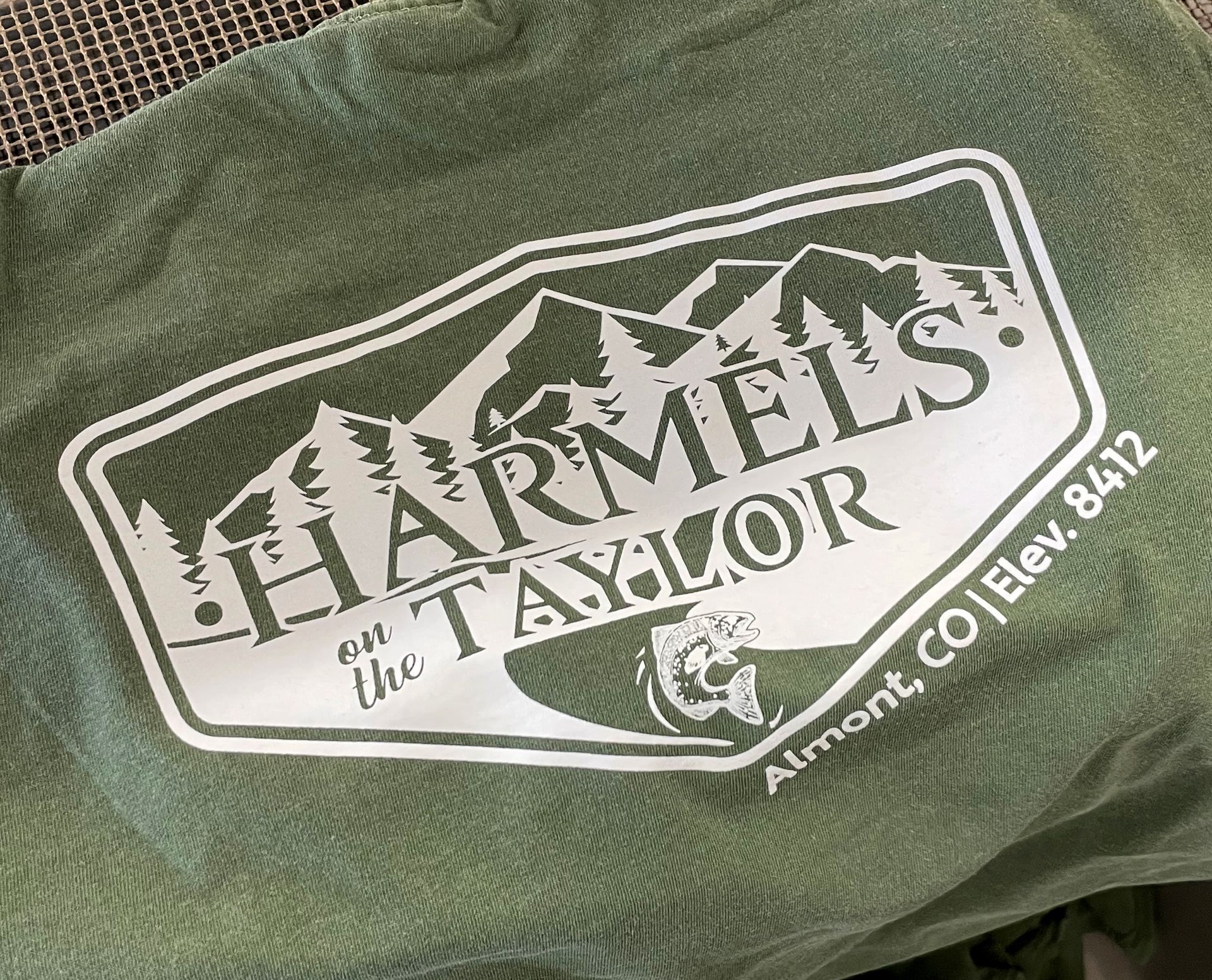 Logo for Harmels on the Taylor, with mountains and text. Green and white colors. Located in Almont, CO, Elev. 8412.