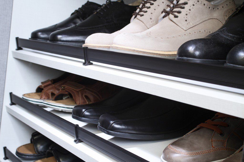 Shoes arranged on white metal shelves in a closet or shoe rack