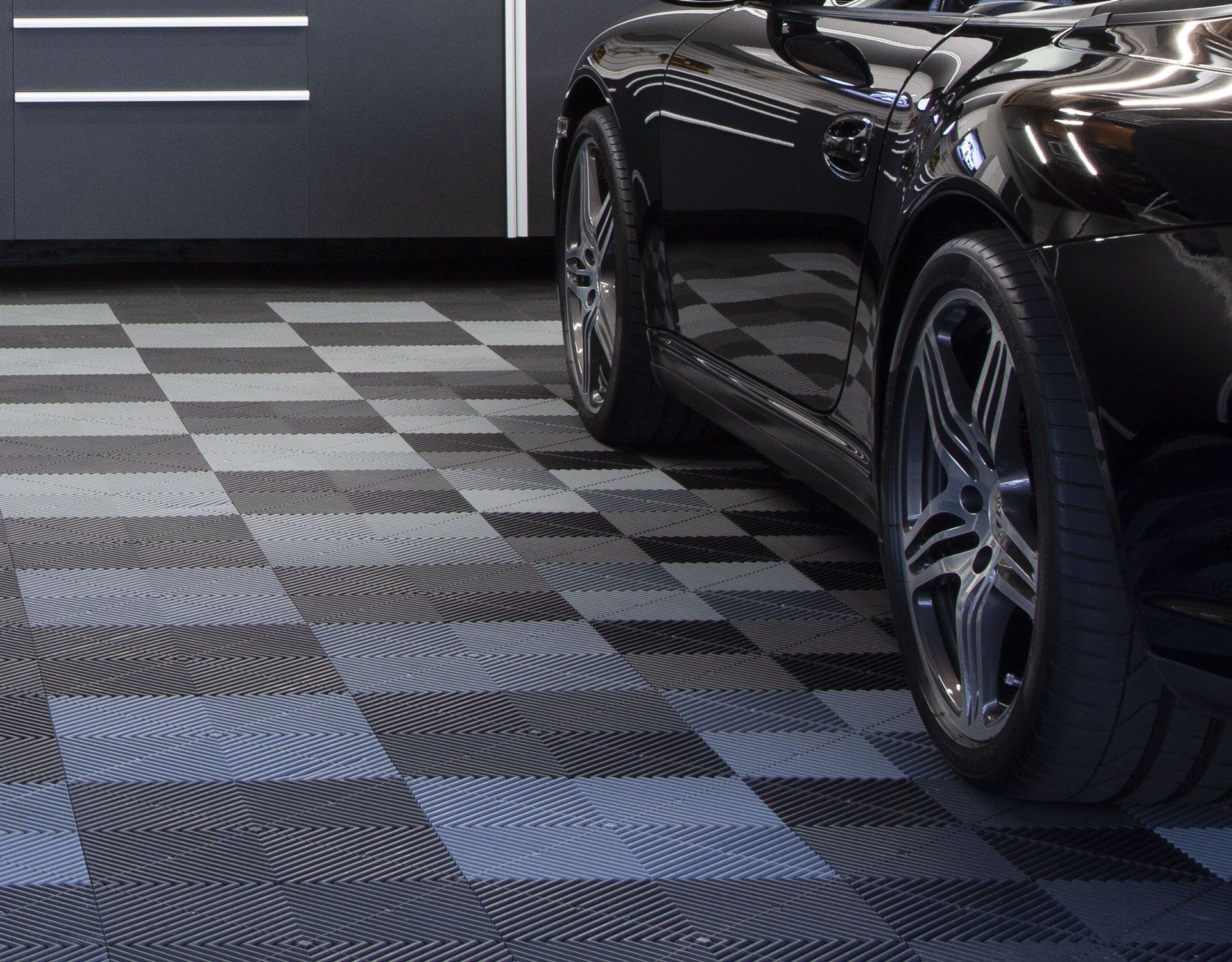 a black car parked in a garage with Swisstrax  floor