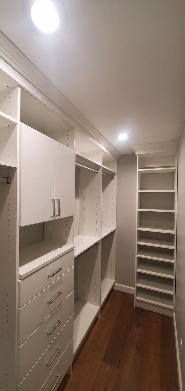 a white walk-in closet with lots of Shelves and drawers