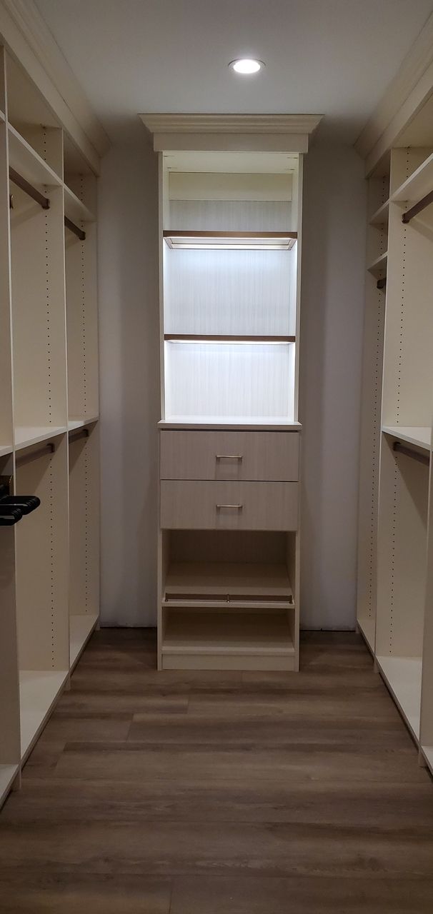a walk-in closet with lots of hanging rods and drawers and shelves