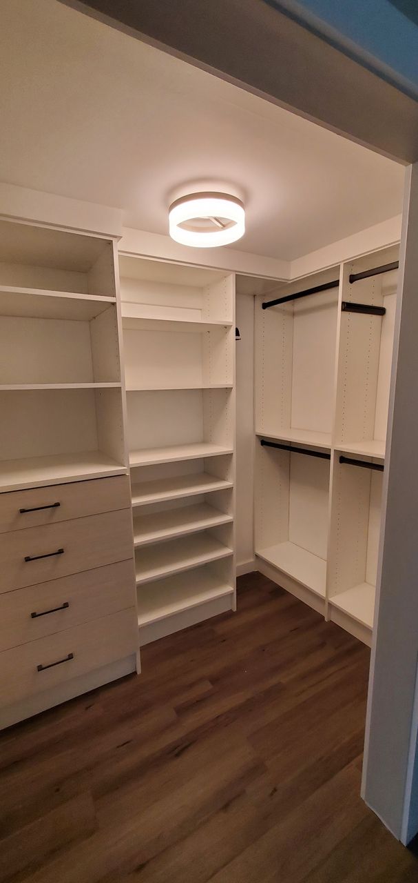 a walk in closet with lots of shelves and drawers .