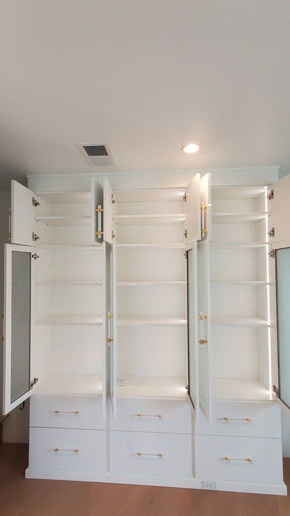 a custom white finish closet system with open glass door cabinet 